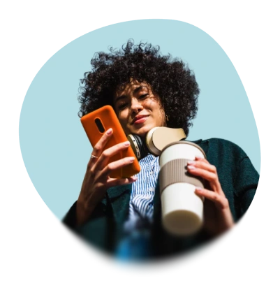 Eine junge Frau schaut auf ihr mobiles Telefon. Sie lacht.